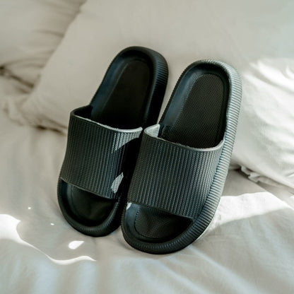 Comfortable stylish black slippers on bed