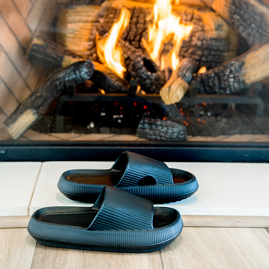 Men's black slippers in front of cozy fireplace