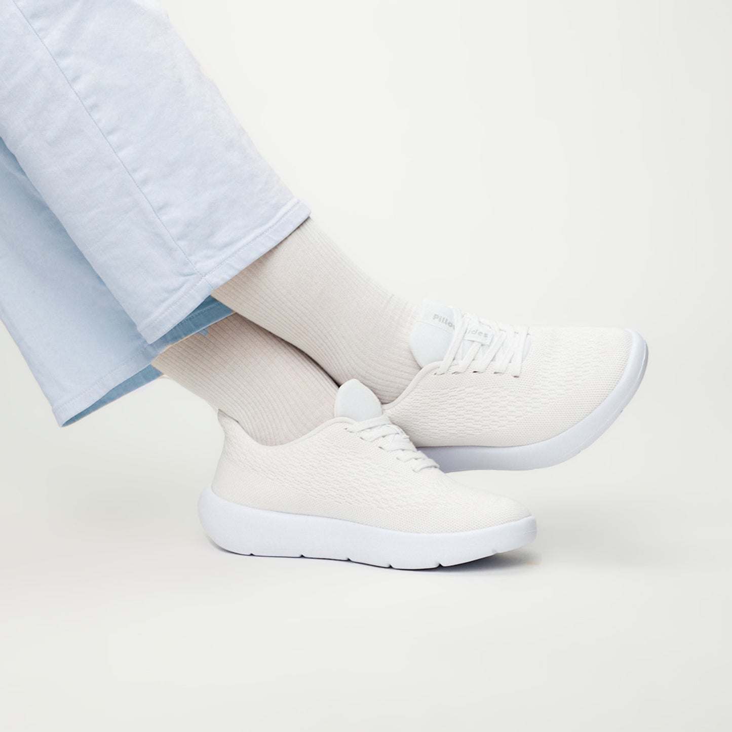 Stock white sneakers being worn with white backdrop