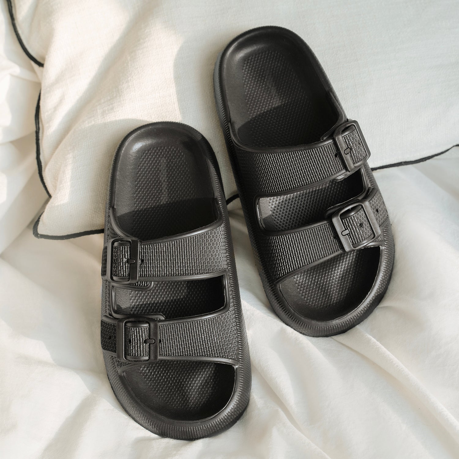 Men's black sandals on a bed