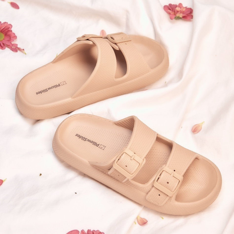 Women's tan sandals on bedding with flowers